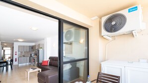 A modern hotel room with a glass door leading to a kitchen and dining area, a dining table set with plates and glasses, and a white cabinet. - Sea Bliss Penthouse with two terraces enjoying side seaviews by Gatewaysmalta (St. Paul's Bay)