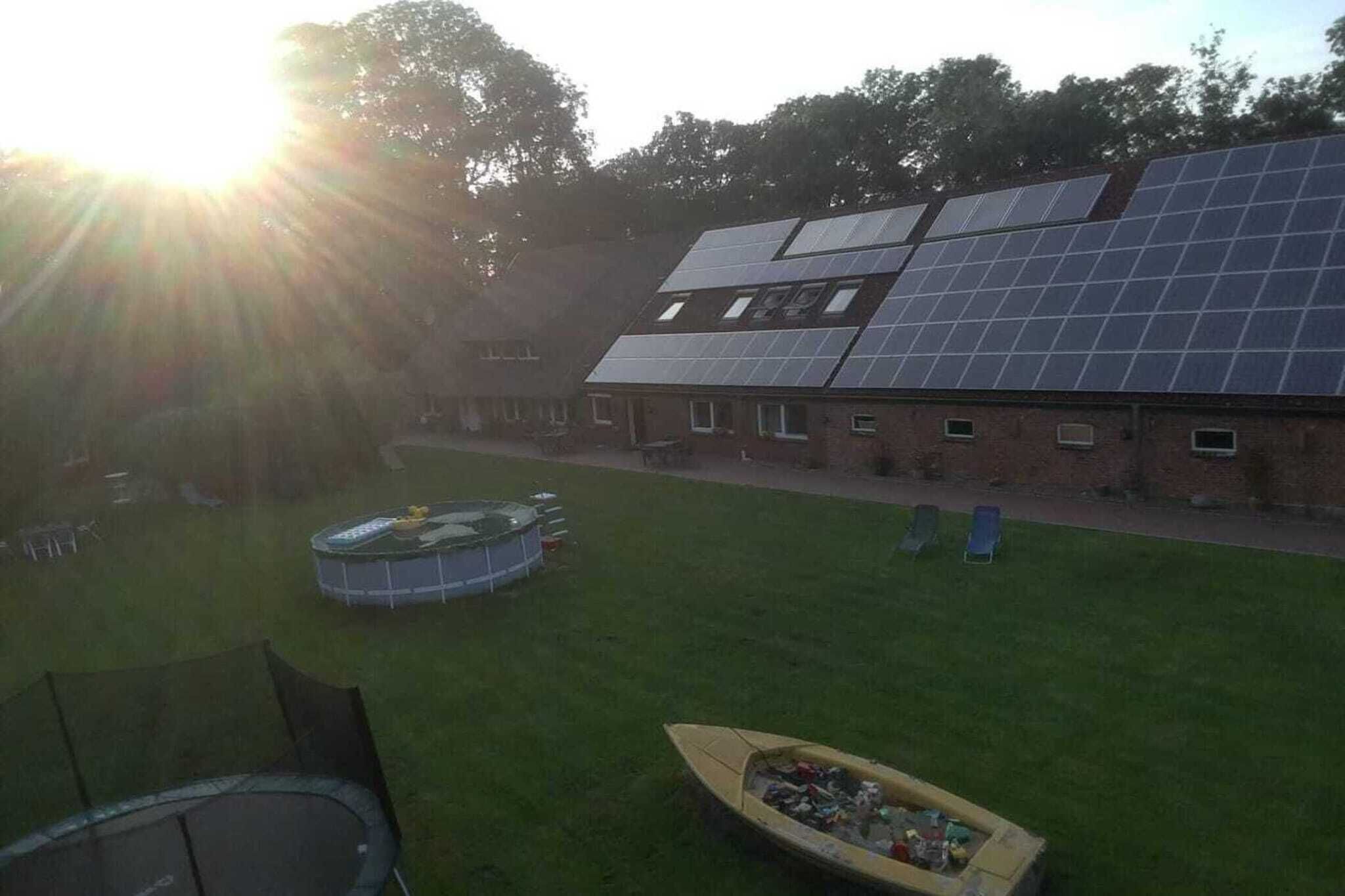 A building with a solar panel array, a swimming pool, and a boat.