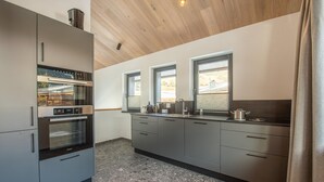 A modern kitchen with a built-in oven, a coffee machine, and a window overlooking a landscape. - Chalet in Wald im Pinzgau near Krimml Falls (Wald im Pinzgau)