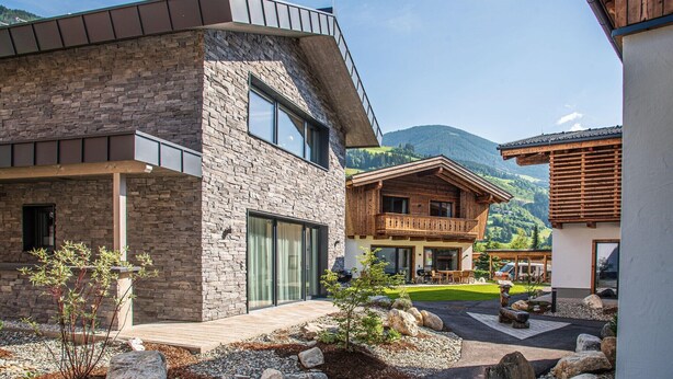 A modern building with a stone facade, large windows, and a wooden balcony. - Chalet in Wald im Pinzgau near Krimml Falls (Wald im Pinzgau)