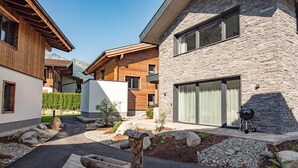 A modern building with a stone facade, wooden balconies, and a barbecue area. - Chalet in Wald im Pinzgau near Krimml Falls (Wald im Pinzgau)