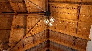 A wooden ceiling with a central light fixture and exposed beams.