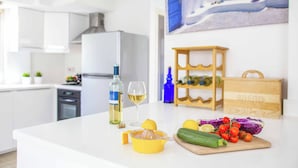 En köksbänk med en juicer, en flaska vitt vin, ett glas och färska grönsaker.