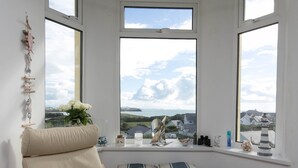 Ein gemütliches Zimmer mit Meerblick, eine hölzerne Truhe und ein Sessel mit dekorativen Kissen.
