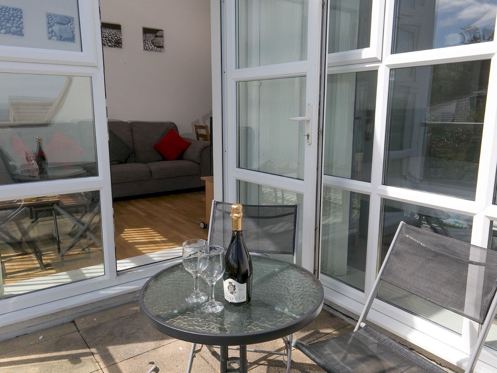 A glass-enclosed patio with a round table, a bottle of wine, and two glasses.