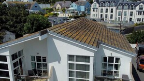 A two-story building with large windows and a balcony on the upper floor. - 2 Bed Sea View Apartment with Balcony Parking - Pass the Keys (Benllech)