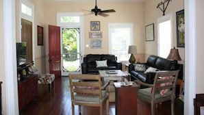 Una sala de estar con ventilador de techo, dos sofás, una mesa de centro y un televisor.