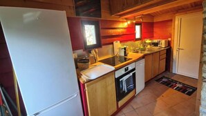 A compact kitchen with wooden cabinets, a white refrigerator, a dishwasher, and a sink. - Small house on the port (Bono)
