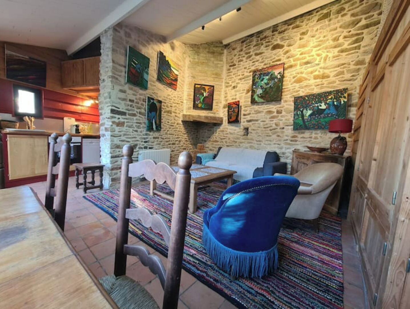 A cozy living room with a stone wall, wooden furniture, and colorful artwork.