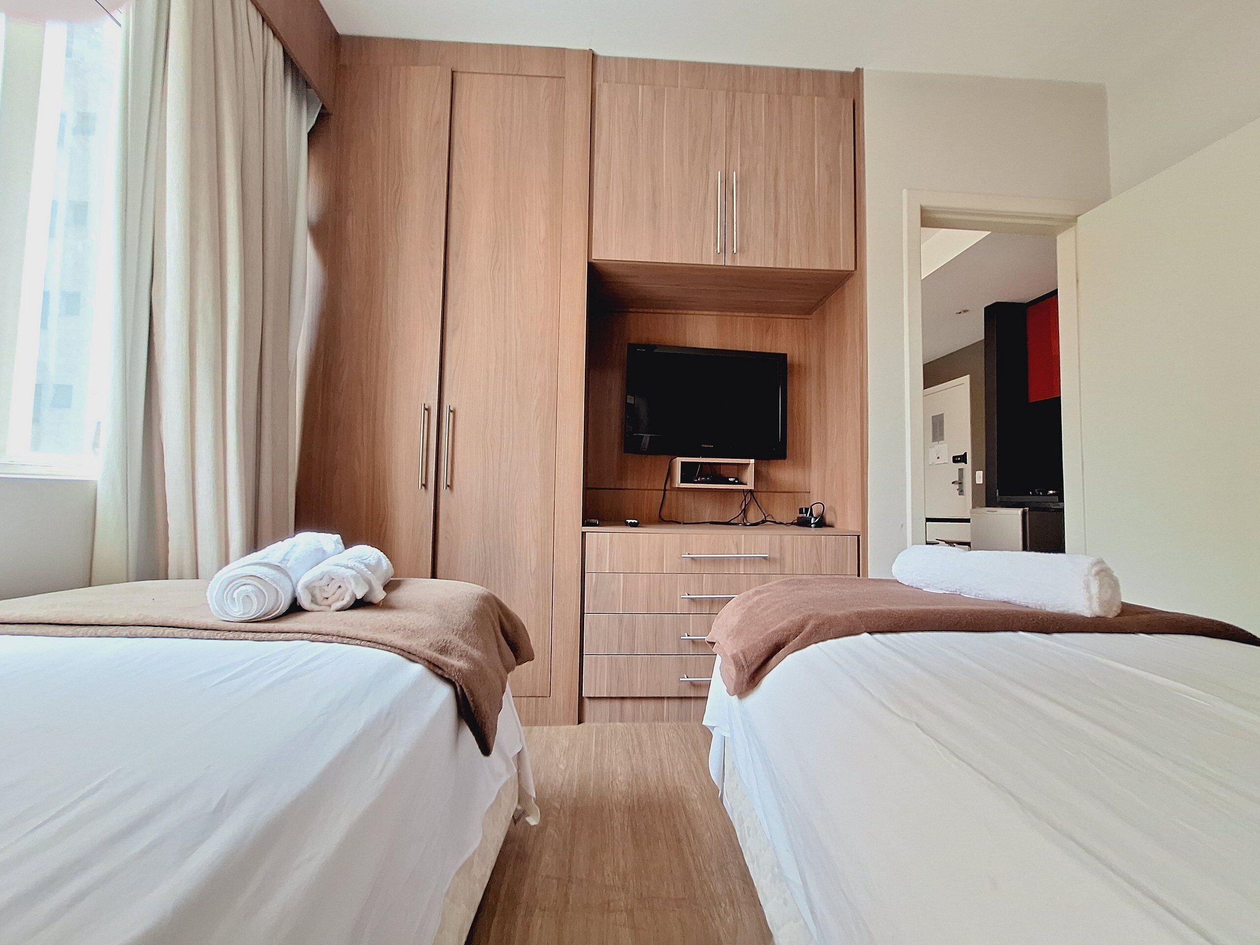 Una habitación de hotel con dos camas, televisión y kitchenette.