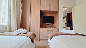 Una habitación de hotel con dos camas, televisión y kitchenette.