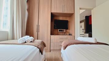 Una habitación de hotel con dos camas, televisión y kitchenette.