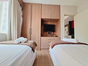 Una habitación de hotel con dos camas, televisión y kitchenette.