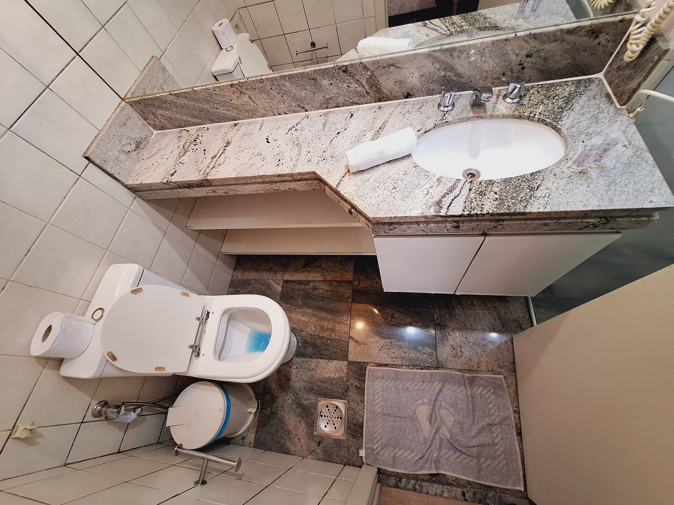 A bathroom with a toilet, bidet, sink, and a shower area.