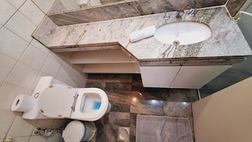 A bathroom with a toilet, bidet, sink, and a shower area.