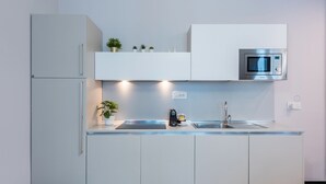 Une cuisine moderne équipée d’un four à micro-ondes encastré, d’un évier et d’une machine à café.