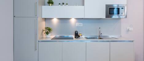 A modern kitchen with a built-in microwave, a sink, and a coffee machine.