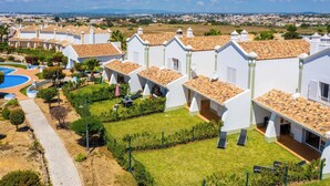 A residential area with white buildings, a swimming pool, and a clear view of the surrounding landscape.