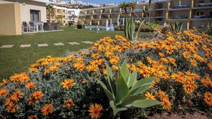 Un hotel con piscina, zona de estar al aire libre y jardín con flores de naranja.