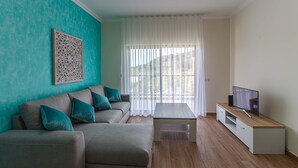 Una sala moderna con un sofá modular, una mesa de centro y un televisor sobre un mueble de madera.