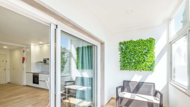 Eine moderne Wohnung mit Küche, Essbereich und einem Balkon mit Korbmöbeln.