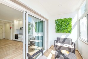 Um apartamento moderno com cozinha, área de refeições e varanda com móveis de vime.