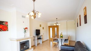 Una sala de estar con chimenea, televisor, comedor con mesa y sillas, y un sofá.