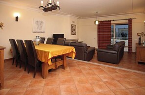 A dining area with a wooden table and chairs, a sofa, and a fireplace.