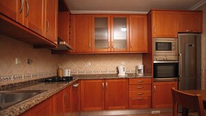 A kitchen with wooden cabinets, a stainless steel refrigerator, a double oven, and a granite countertop.