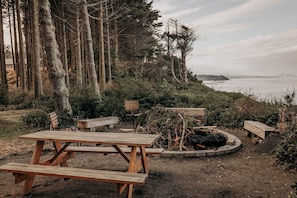 Ein Picknickbereich mit Holzbänken und Picknicktischen, umgeben von Bäumen und Blick auf das Wasser.