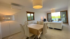 A dining area with a table and chairs, a ceiling light, a window, and a sliding glass door leading to an outdoor area. - Villa Filipa III - Beachfront with Jacuzzi (Albufeira)