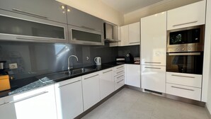 A modern kitchen with stainless steel appliances, white cabinetry, and a black countertop. - Villa Filipa III - Beachfront with Jacuzzi (Albufeira)