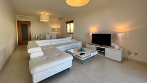 A modern living room with a large white sectional sofa, a flat-screen TV, and ambient lighting. - Villa Filipa III - Beachfront with Jacuzzi (Albufeira)