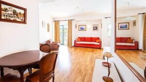 Un salón amplio con piso de madera, una mesa de comedor con sillas y dos sofás rojos.