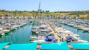Una marina con numerosos barcos amarrados en aguas tranquilas, rodeada por un paisaje montañoso.