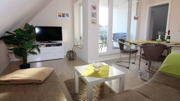 A living room with a TV, sofa, and dining area.