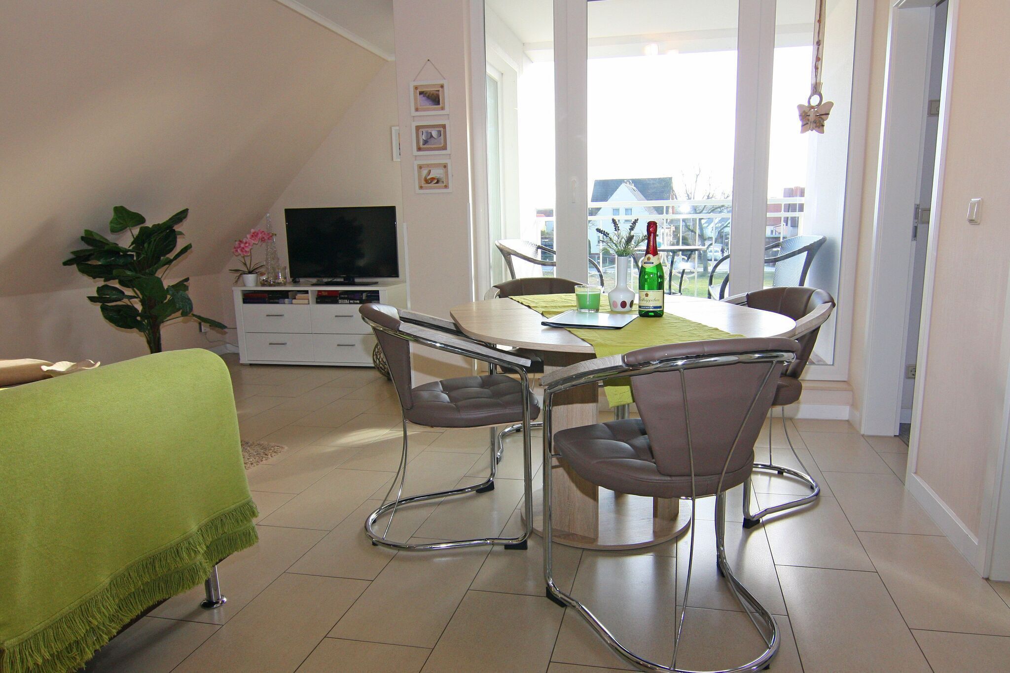 A dining area with a table and chairs, a television, and a plant.