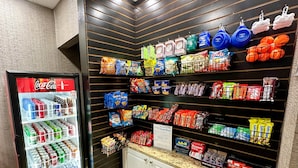 Un espace dédié à la présentation de collations et de boissons, où l’on trouve une variété de produits, notamment des en-cas, des boissons et un réfrigérateur rempli de produits Coca-Cola.