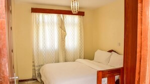 A bedroom with a bed, curtains, and a wooden chair.