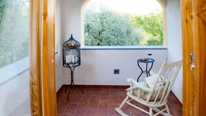 A balcony with a rocking chair, a small table, and a birdcage. - Villa in Vinci with Pool & Panoramic Views (Lamporecchio)