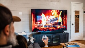 A living room with a television displaying a fireplace, a sofa, and a coffee table.