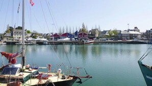 Uma marina com barcos atracados, céu claro e edifícios ao fundo.