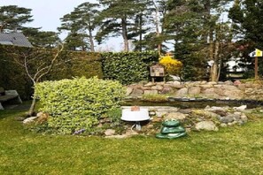 Ein Garten mit Teich, Steinen und einer kleinen Holzkonstruktion.