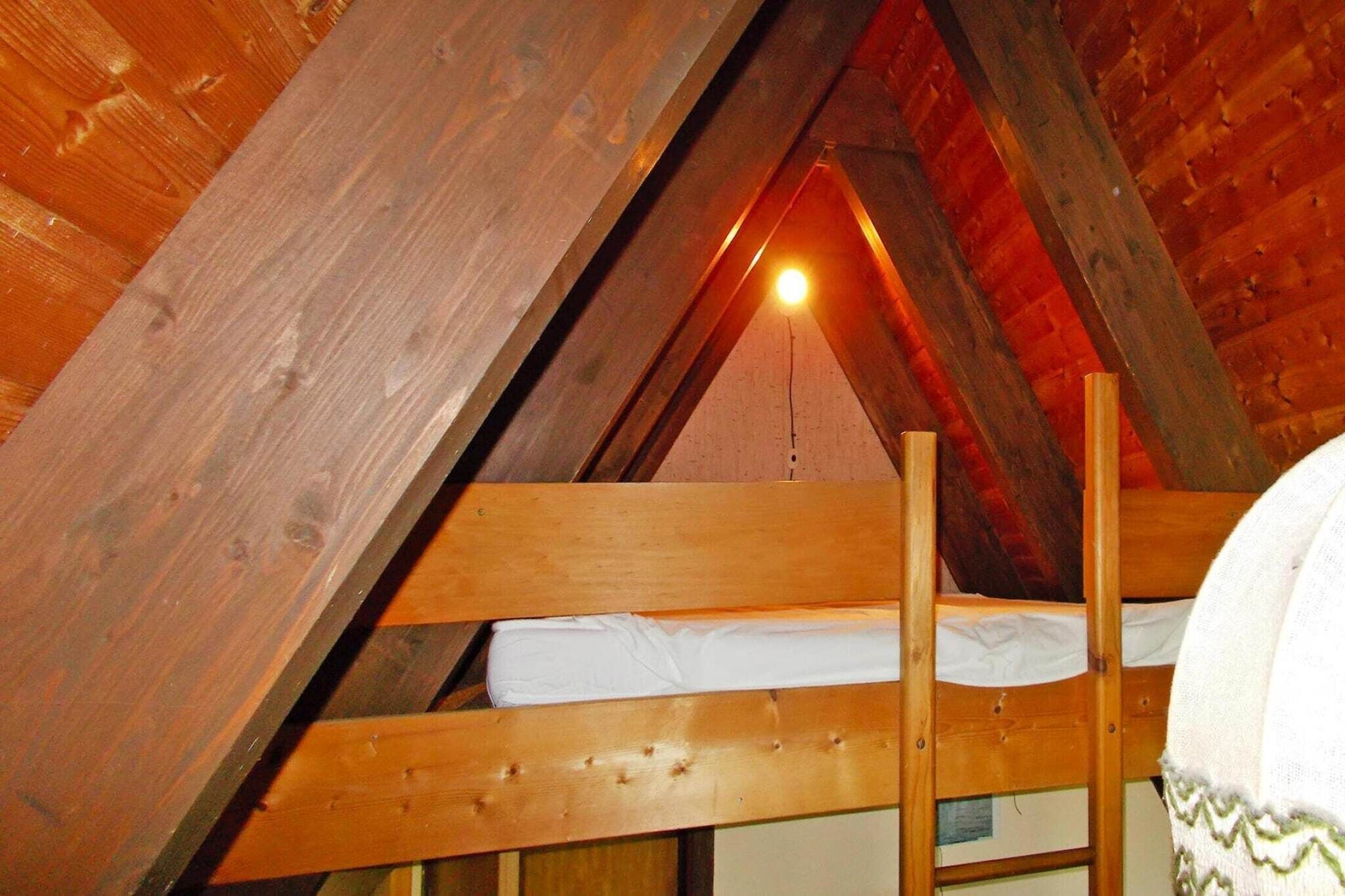Un letto a castello in legno in una stanza con travi a vista e soffitto spiovente.