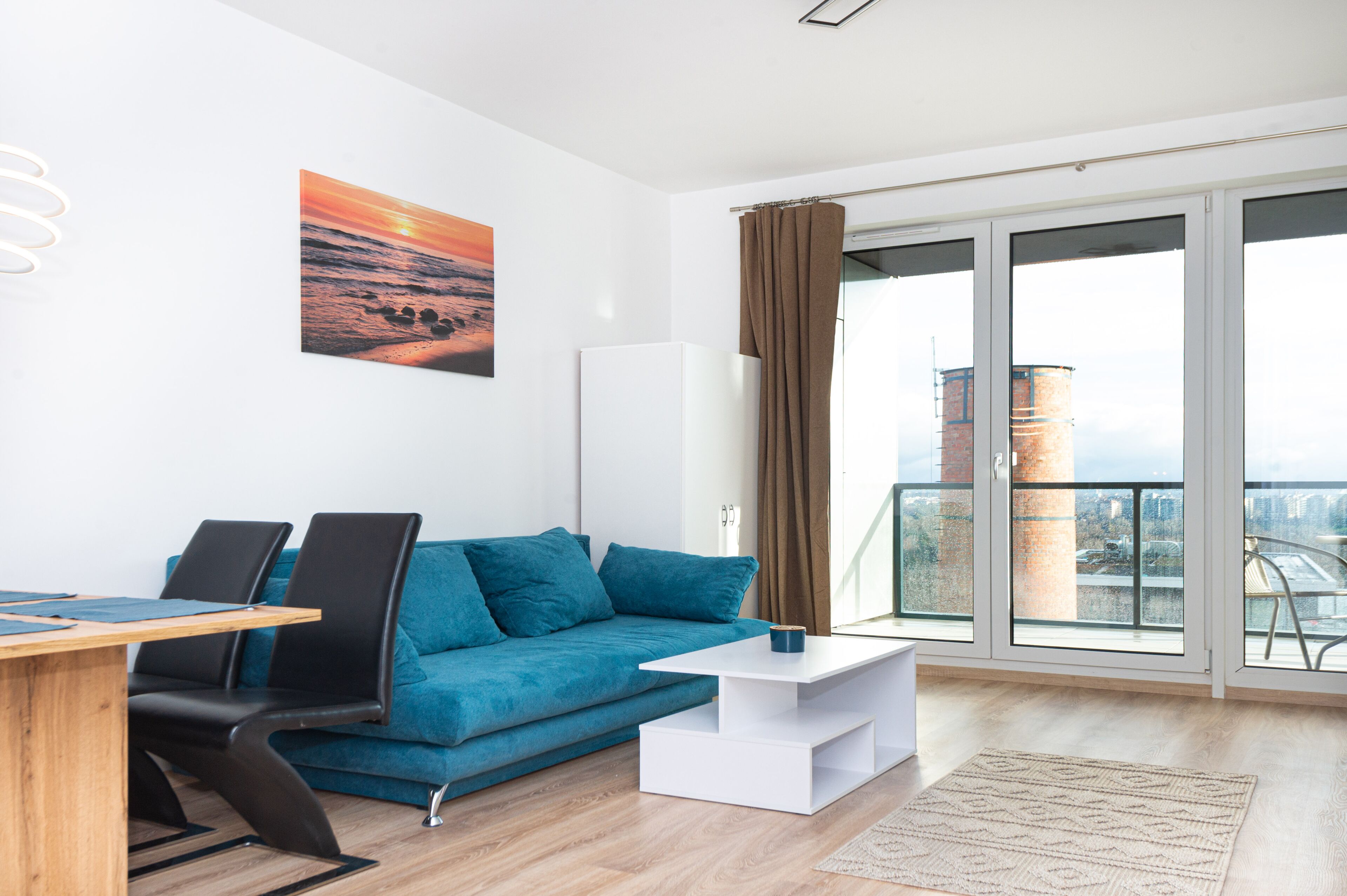 Un saló modern amb un sofà blau, una taula de centre blanca i una finestra gran amb cortines.