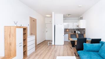 Um apartamento moderno com cozinha compacta, área de jantar e sala de estar.