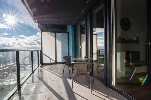 A balcony with a view of the city, a table with chairs, and a clock on the wall. -  WaterFront City Apartments by FirstHost (Budapest)