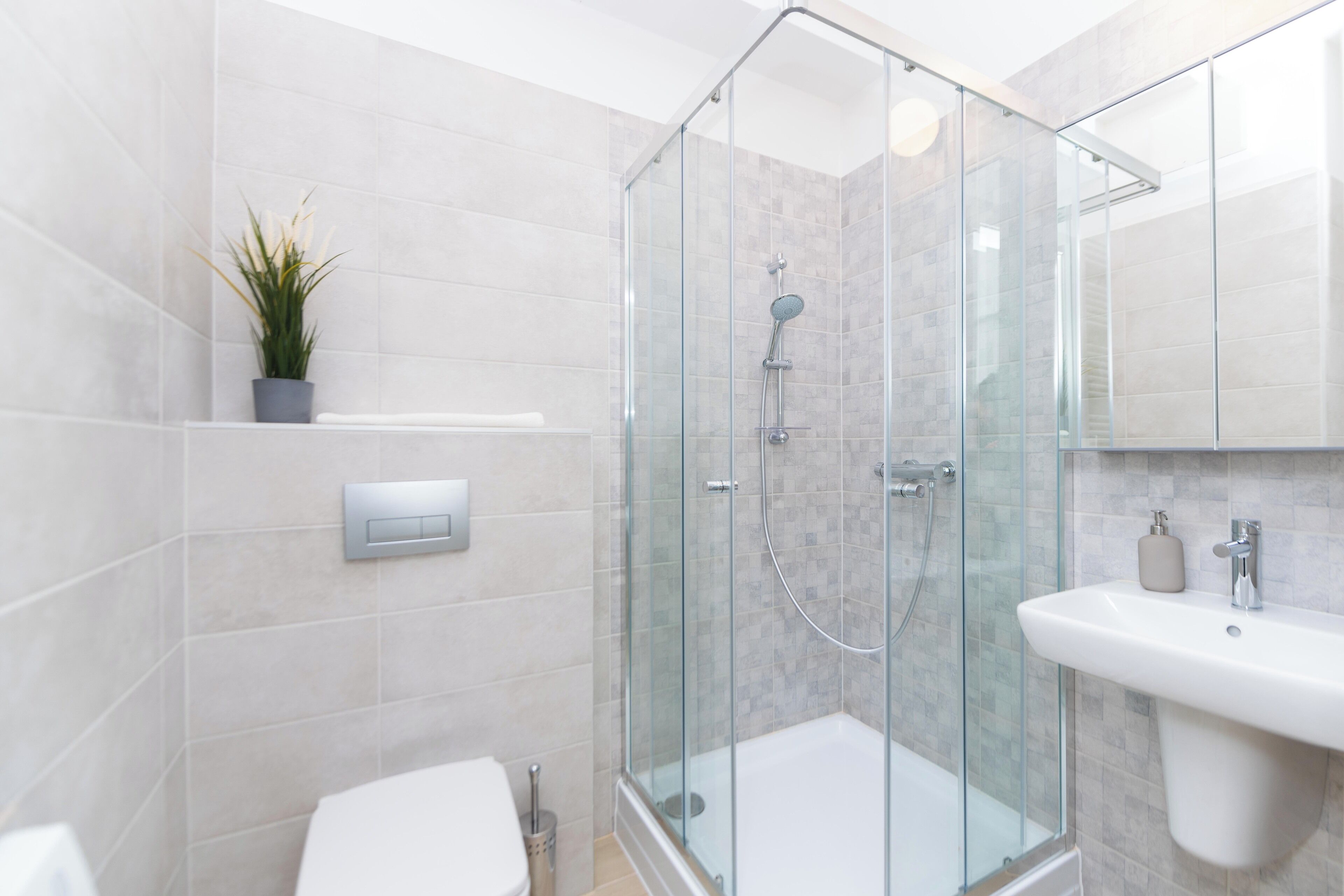 Une salle de bain moderne avec une douche à parois de verre, un lavabo blanc et des toilettes.