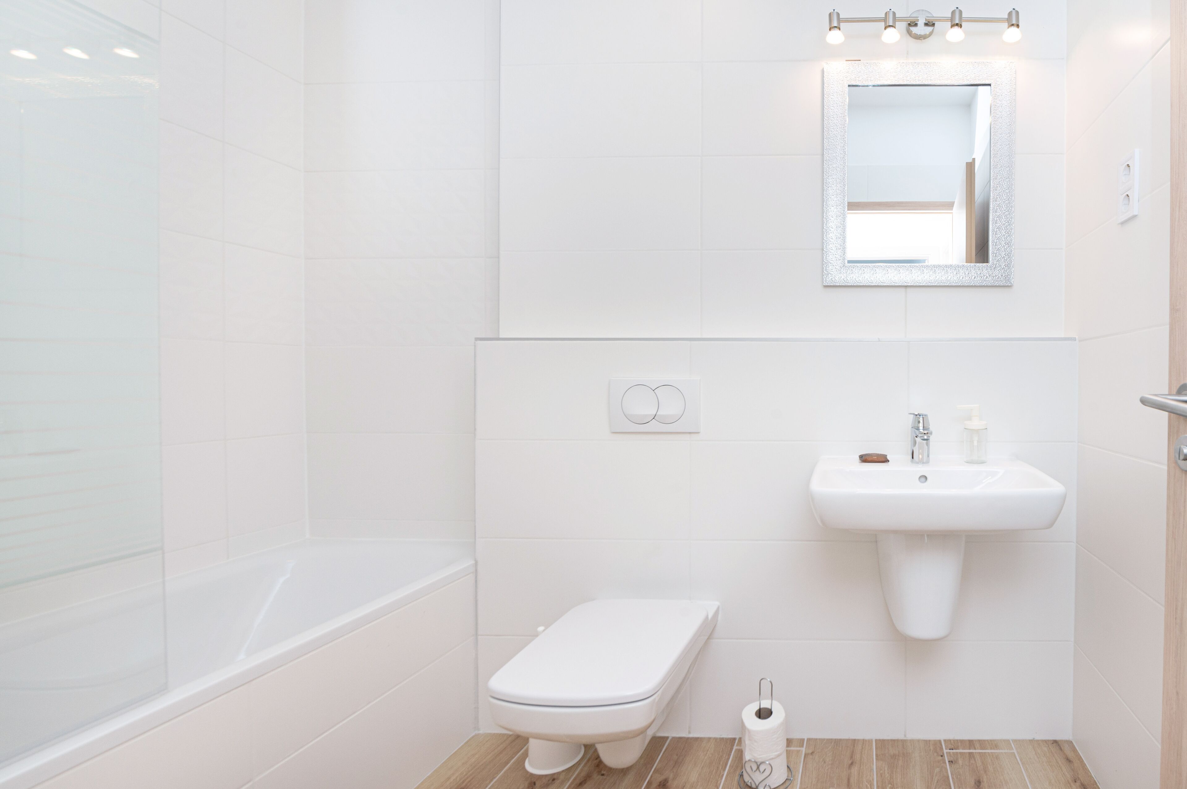 A bathroom with a white toilet, a sink with a mirror above it, and a shower area.