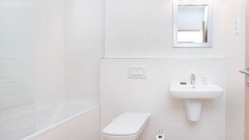 A bathroom with a white toilet, a sink with a mirror above it, and a shower area.